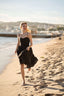 A girl recreating Brigitte Bardot’s run on the beach in Cannes, wearing a Gaâla cotton/linen black Bardot dress.