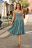 A laughing redhead in Cannes wearing a sunhat and a blue cotton/linen Gaâla Bardot dress, playfully lifting up the skirt to show a voluminous petticoat underneath.