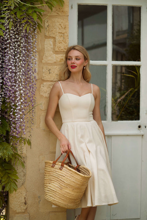 A beautiful blonde girl surrounded by flowers in scenic Normandy, wearing a cream colored corset dress.