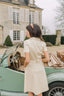 A girl in Normandy, France, leaning against a car and wearing Gaâla Paris belted button down Paris dress