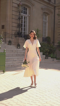 A bride on her wedding day in Paris wearing a silk dress with flutter sleeves and an open back from Gaâla