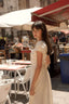 Brunette girl in a marketplace in Sicily, wearing a vintage inspired cream Gaâla linen dress