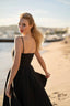 A blonde girl recreating Brigitte Bardot’s run on the beach in Cannes, wearing a Gaâla cotton black Bardot dress.