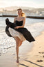 A blonde recreating Brigitte Bardot’s iconic run on the beach in Cannes, wearing a Gaâla cotton/linen black Bardot dress.