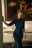 Girl standing in a luxe looking room in Milan wearing a bodycon blue silk evening dress