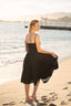 A blonde girl recreating Brigitte Bardot’s run on the beach in Cannes, wearing a Gaâla linen black Bardot dress.