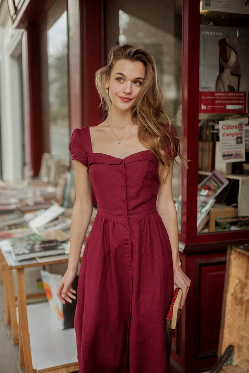 A blonde long haired girl in Paris at a vintage book shop wearing a bordeaux button down Gaâla dress