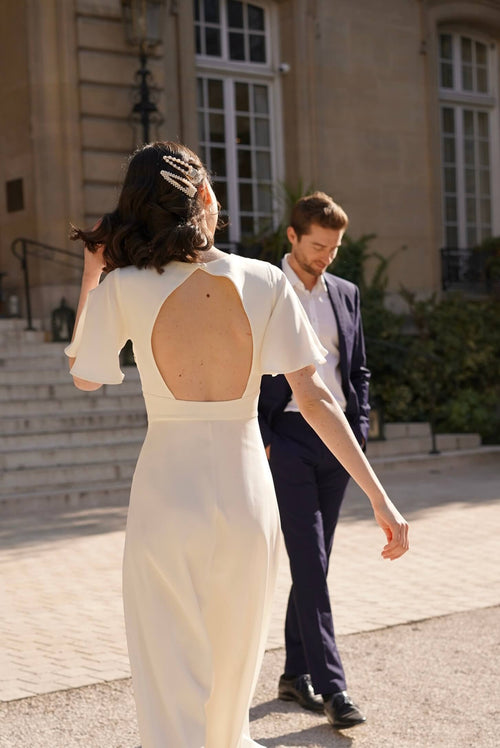 A bride in Paris wearing a long silk dress with flutter sleeves and an open back 