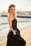 A blonde girl recreating Brigitte Bardot’s iconic run on the beach in Cannes, wearing a Gaâla linen black Bardot dress.