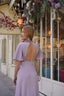 A redhead in front of a cafe in Paris wearing a long silk lilac dress