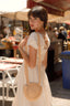 Brunette girl in a marketplace in Sicily, wearing a vintage button down cream Gaâla linen dress